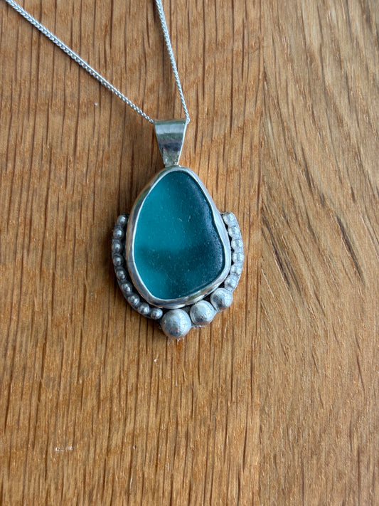Colgante con cristal de mar en tonos turquesa engarzado en plata 925
Diseño artesanal